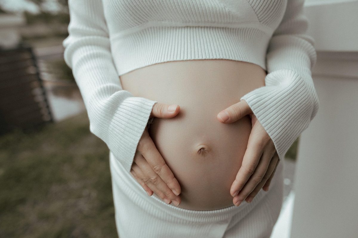 Mulher grávida com expressão preocupada em ambiente de trabalho