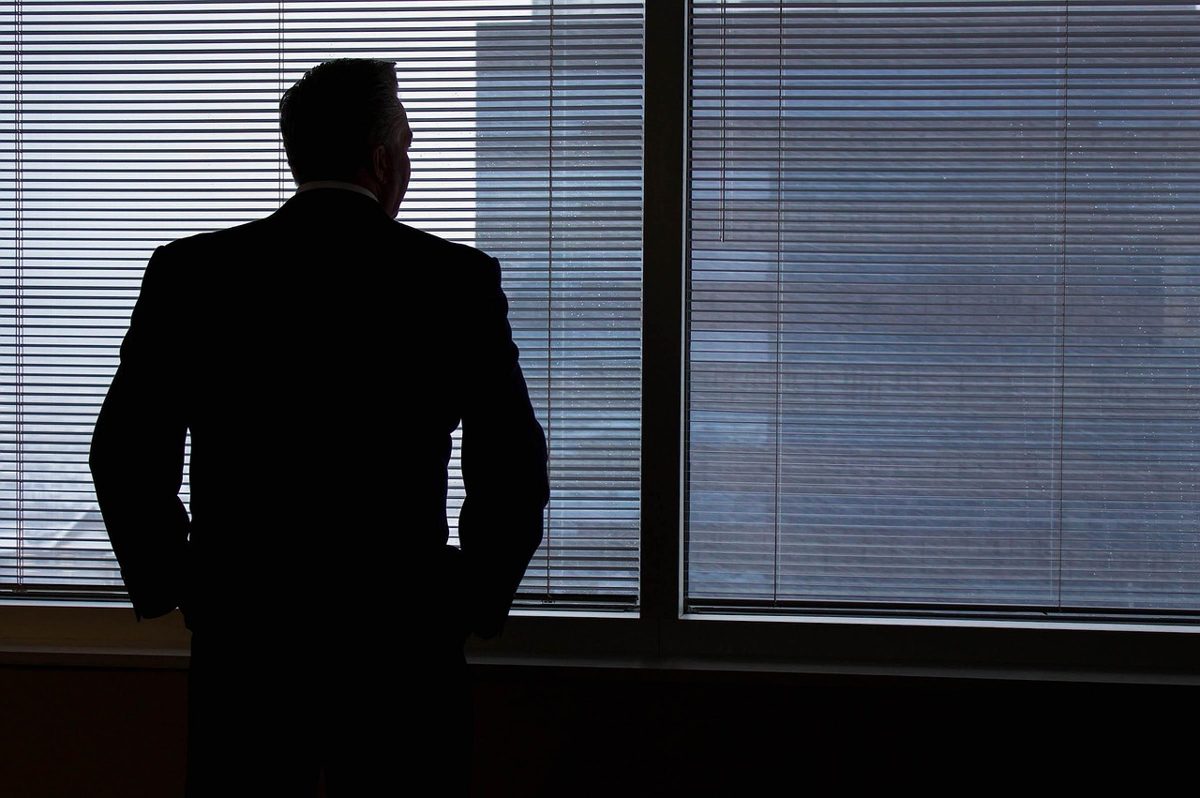 Trabalhador de uniforme olhando o relógio no fim do expediente com uma folha de ponto na mão